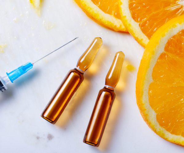 Vitamin C, natural anti aging cosmetics serum and syringe with ornge fruit slices